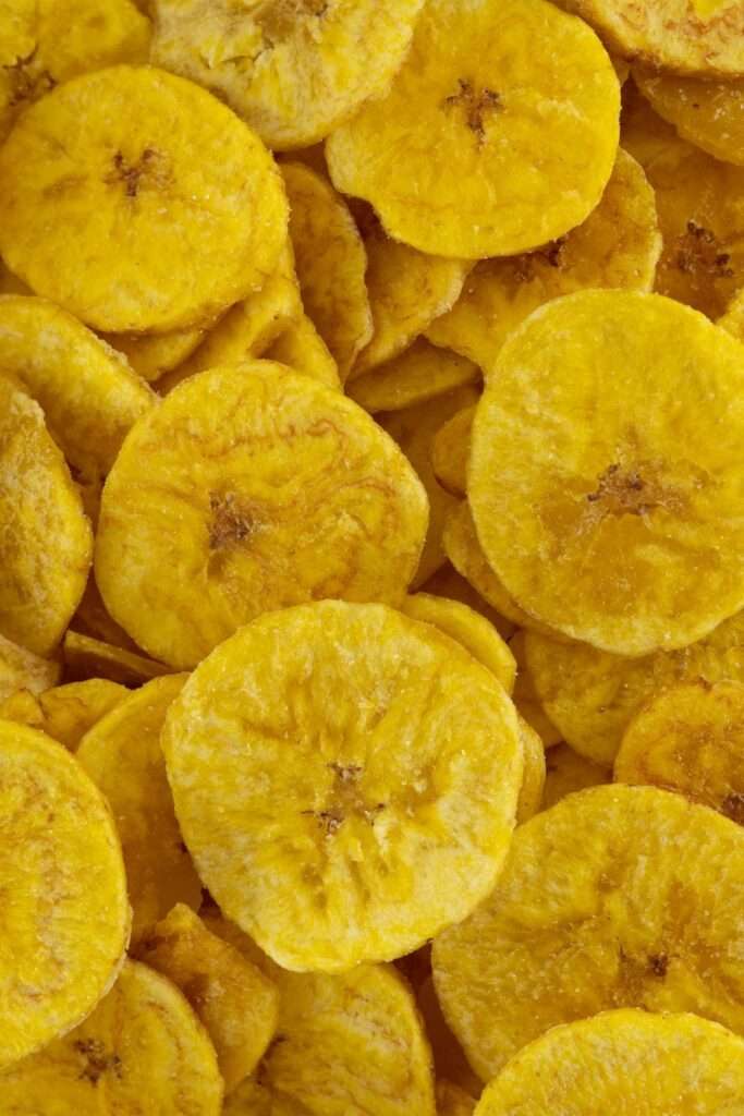 A close-up view of several yellow plantain chips, perfectly stacked and overlapping each other, showcases the delightful result of dehydrating fruits using an air fryer.